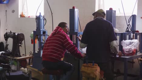 two mixed race men discussing in factory