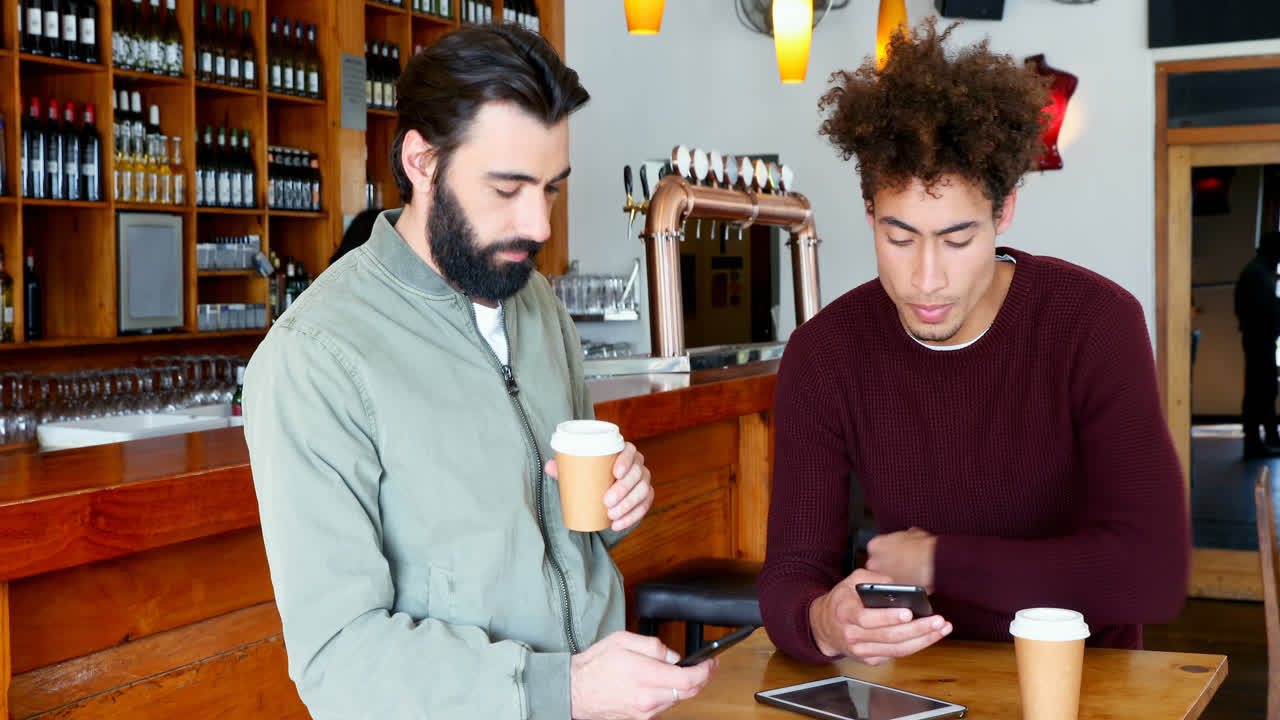 Amici che usano lo smartphone mentre prendono un caffè 4K