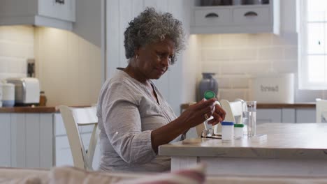 senior african american woman looking at empty medication container while sitting at home