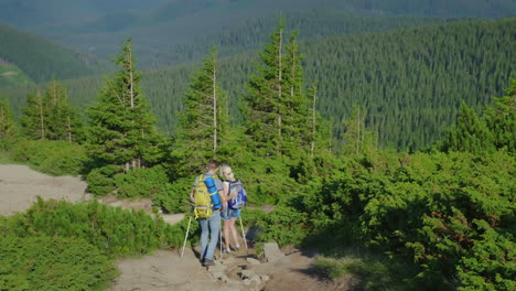 turistas un hombre y una mujer con mochilas en la espalda descienden por el sendero de montaña 4k video