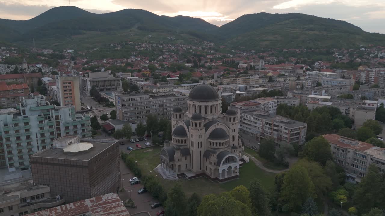 Aerial drone approach to Deva’s cathedral, revealing its architectural details and distant mountains