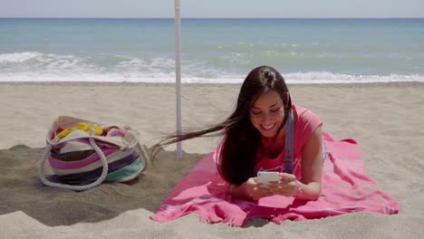 Mujer-Joven-Enviando-Mensajes-De-Texto-Mientras-Se-Relaja-En-La-Playa