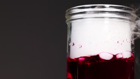 un vaso con líquido rojo y hielo seco crea un efecto de humo y burbujas en un entorno controlado