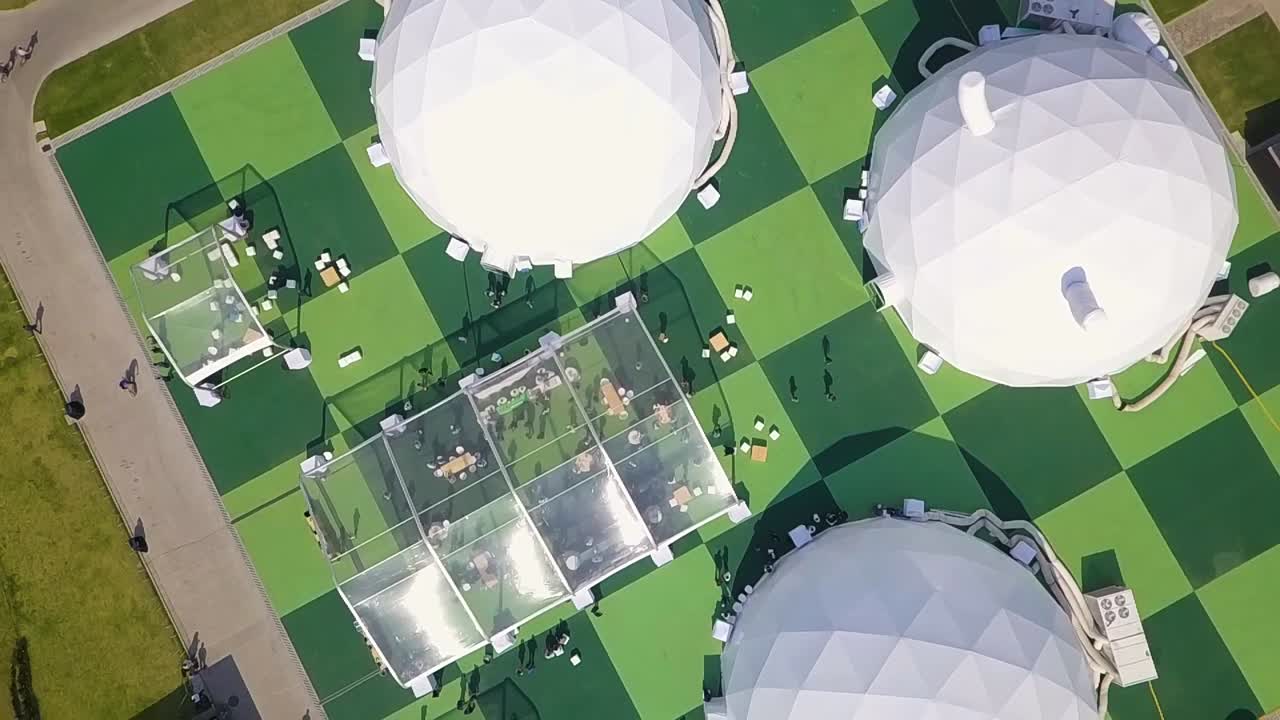 Aerial view of spherical tents with people gathering around them.