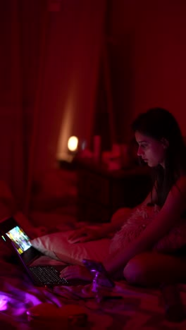 teenage girl watching a movie on laptop in a red-lit bedroom