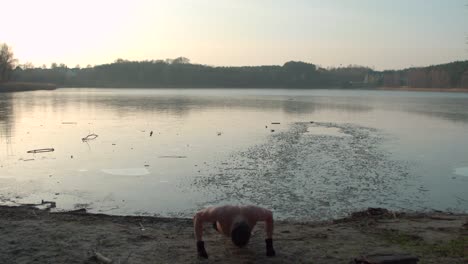 joven haciendo flexiones cerca de un lecho de lago congelado