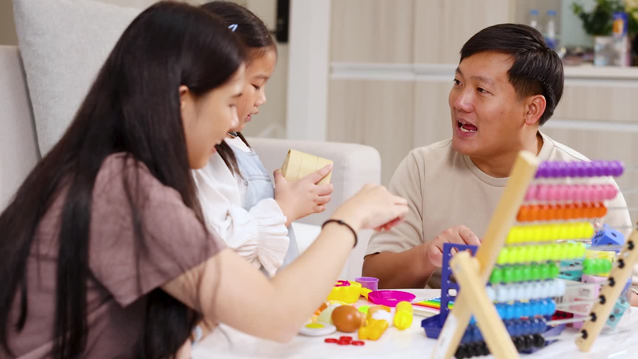 พ่อแม่และลูกมีปฏิสัมพันธ์กับของเล่นสีสันสดใสและลูกคิดในห้องนั่งเล่นที่สดใสและร่าเริง