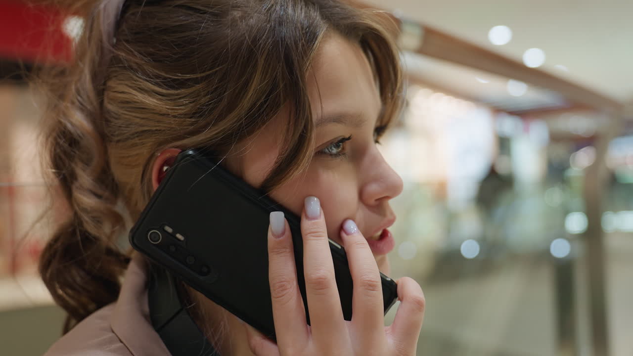 Primer plano de una chica hablando por teléfono, joven conversando por teléfono, adolescente hablando por teléfono en un centro comercial, primer plano de una adolescente hablando por teléfono móvil en un centro comercial