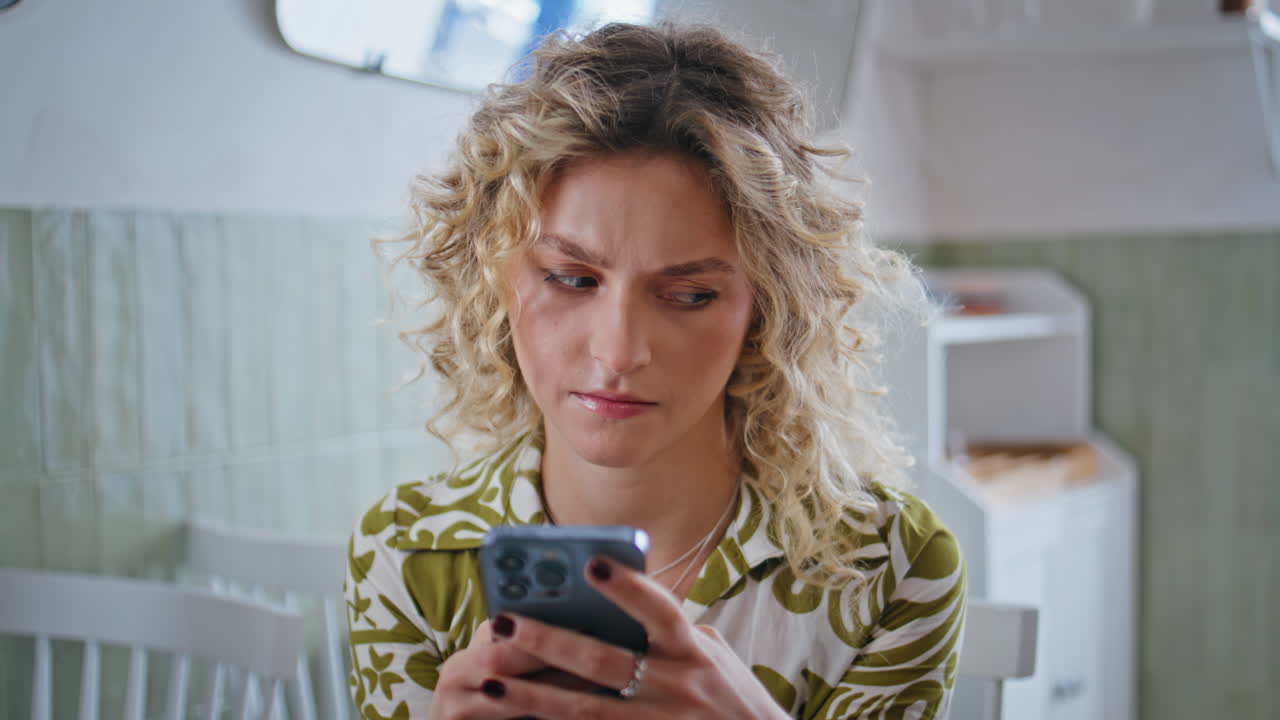 Primo piano di una donna d'affari accigliata che guarda lo schermo dello smartphone seduta in un bar tranquillo