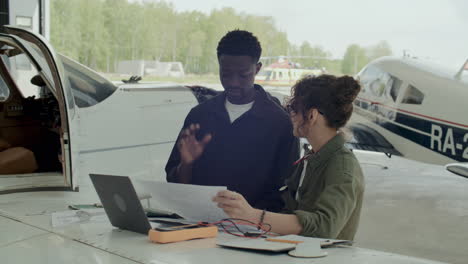 two aircraft mechanics discussing technical documents in hangar