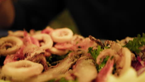 man picking up shrimps from the fried fish appetizer at the restaurant