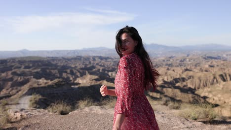 woman in red floral dress overlooking a scenic arid mountain landscape