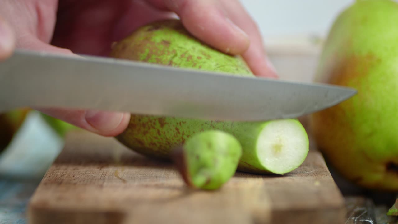 mano masculina con un cuchillo cortar la pera en rebanadas redondas.