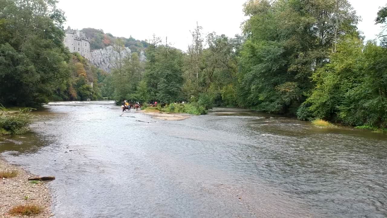 Sorvolando un fiume verso un gruppo di cavalieri con un castello sullo sfondo.