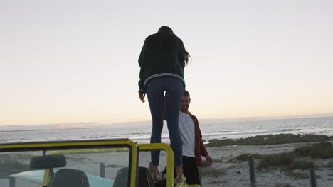 Happy-caucasian-couple-getting-out-of-beach-buggy-by-the-sea