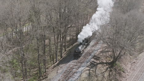 Slow-motion-aerial-drone-shot-of-a-steam-train-engine-moving-down-the-tracks-in-Chattanooga,-TN