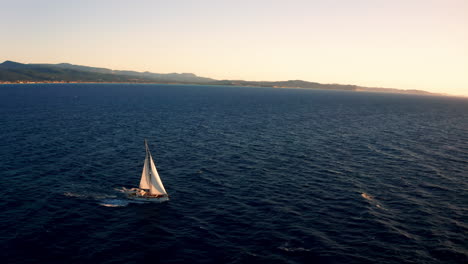 aerial drone view of a boat sailing offshore at sunset in greece