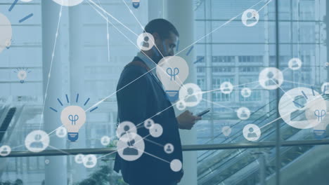 Animation of network of profiles and bulb icons over biracial businessman using smartphone at office