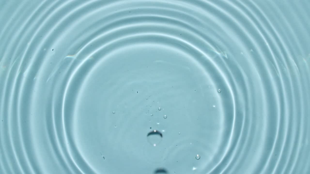 물방울이 물속으로 떨어지는 느린 움직임과 파란색 배경에 분산되는 물의 원. 물방울 스플래시 파란색.