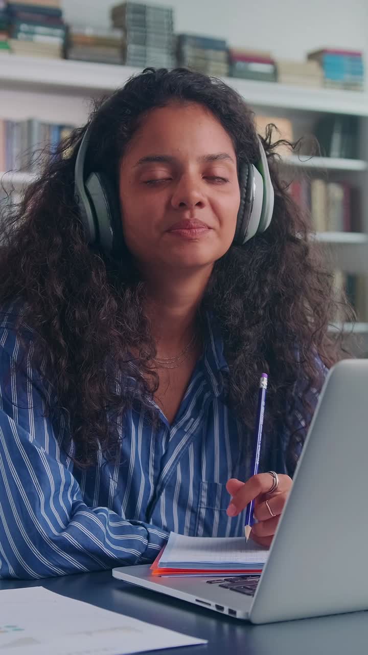 Young woman studies in a quiet space with headphones on