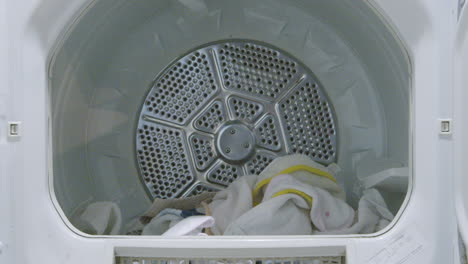 dryer door opens revealing a pile of freshly dry towels doing laundry still shot