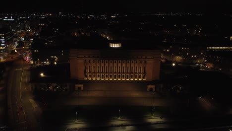 Black-night-aerial-pulls-back-from-Parliament-House-building,-Helsinki