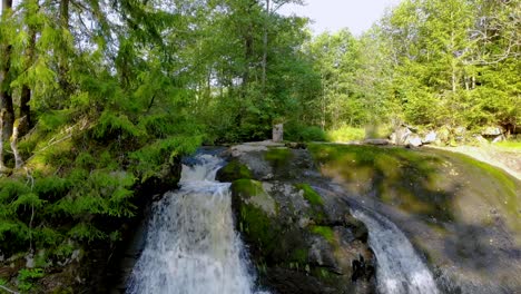 zoet water cascade stroomt door de rotsen in het midden van dicht bos