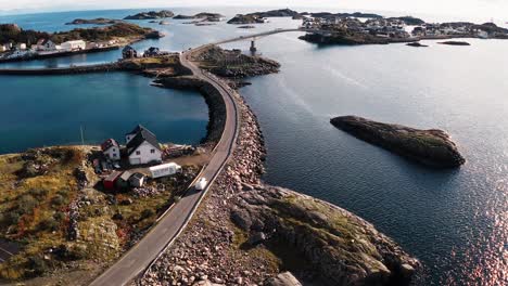 Aerial-shot-of-a-white-camper-van-arriving-in-Henningsvær,-next-to-a-fish-drying-racks,-Lofoten-Islands,-Norway