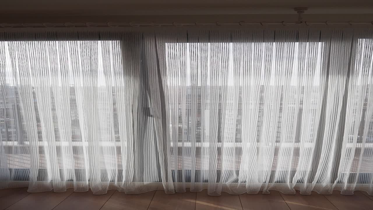 cortinas blancas con vista a la ciudad desde la ventana del apartamento