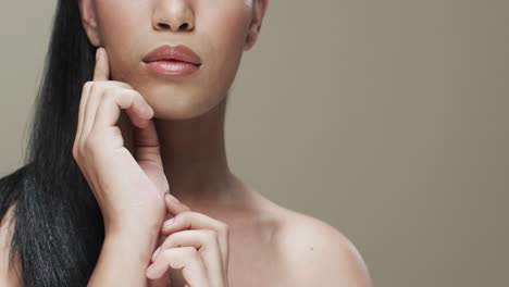 biracial woman with black hair and make up touching her face, copy space, slow motion