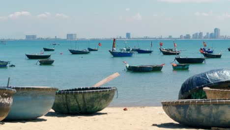 a stationary closeup footage of round vietnamese fishing boats resting along the seashore in a sunny afternoon together with the regular boats anchored near the shoreline.