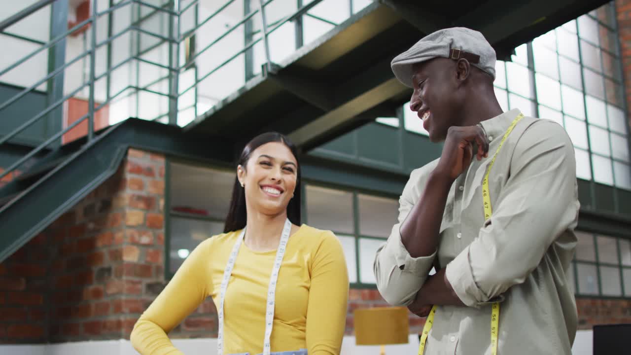 Happy diverse fashion designers wearing the tape measures discussing work at office