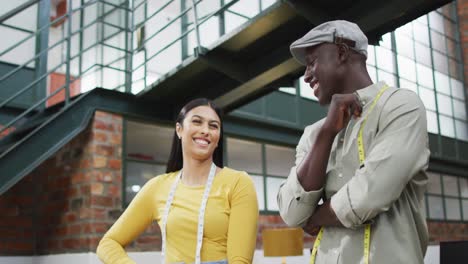 diseñadores de moda diversos felices usando las medidas de cinta discutiendo el trabajo en la oficina