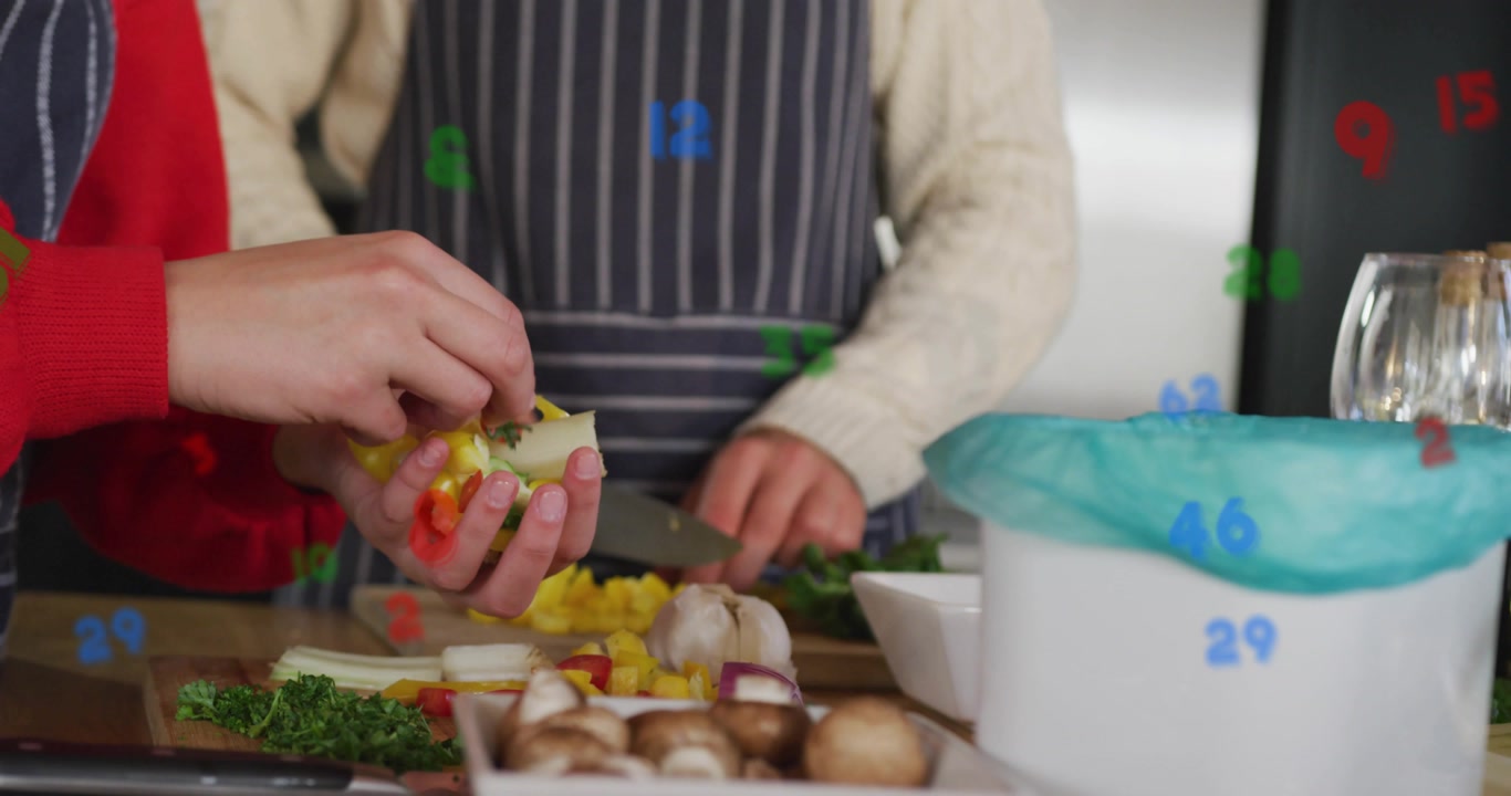 Home cooks lifting halved yellow pepper, coring seeds on board and slicing strips for food prep