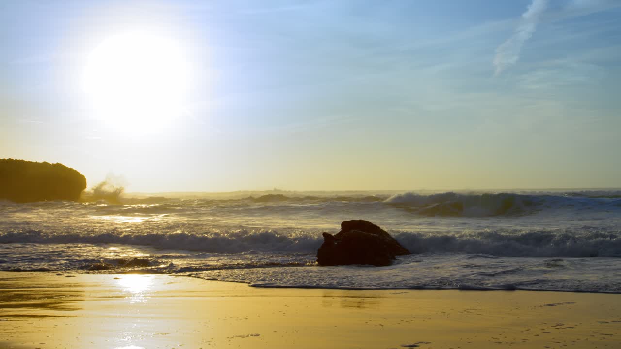 cascais guincho sintra 해변에서 선명한 아름다운 일몰 동안 다채로운 황금 시간 빛이 슬로우 모션 와이드 샷으로 바위에 충돌하는 파도가 튀는 스프레이