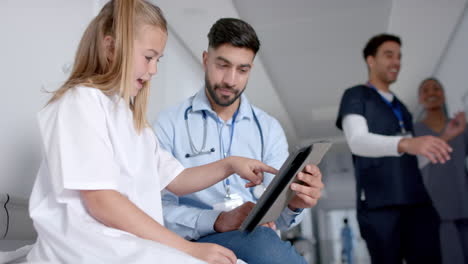 young asian doctor reviews medical information on a tablet with a caucasian girl, with copy space