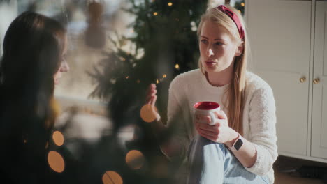 beautiful woman with coffee cup talking to sister at home during christmas