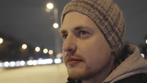 man standing in night street, close up face view moving back