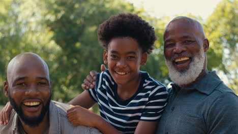 Portrait-Of-Loving-Multi-Generation-Male-Family-Standing-Outdoors-In-Garden-Park-Or-Countryside