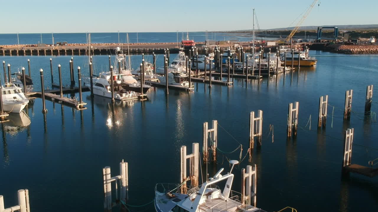 Cinematic drone video harbour with many big boats during sunset with warm sun light on quiet place