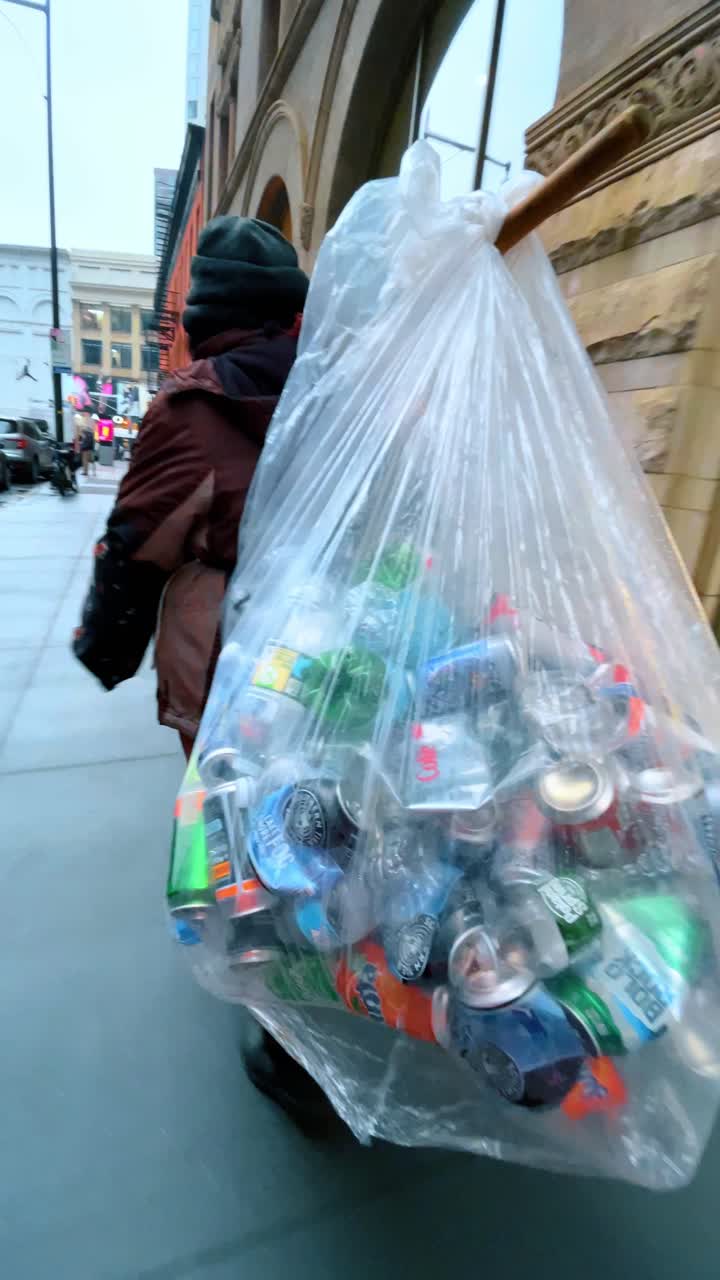 New York, USA, 2 novembre 2022: Persona che trasporta bottiglie riciclabili su un marciapiede cittadino. Persona che trasporta una grande borsa trasparente con bottiglie di plastica, effetto mosso, marciapiede urbano, inquadratura verticale.