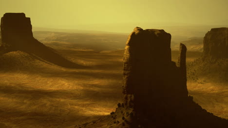 Vast desert landscape features towering rock formations under a golden sky