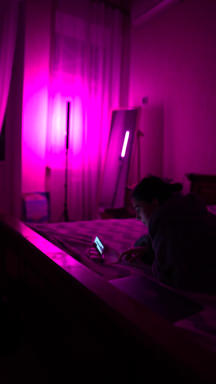 mujer usando el teléfono en un dormitorio iluminado de púrpura por la noche