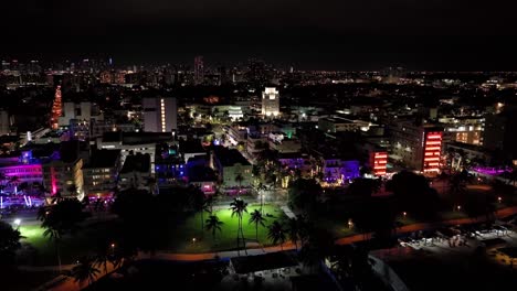 vibrante imágenes aéreas de drones nocturnas de miami, estados unidos: lento descenso hacia adelante movimiento desde la orilla del mar, mostrando edificios, carreteras, rascacielos, con muchas luces de diferentes colores