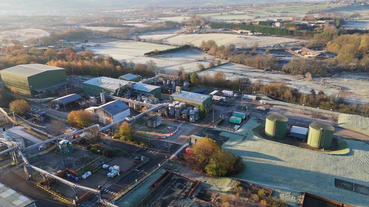 Imagens aéreas de drone de um pátio industrial e comercial. Instalação de armazenamento com vistas matinais de trabalhadores e veículos em movimento, com homens trabalhando. Contêineres e maquinário de planta química.