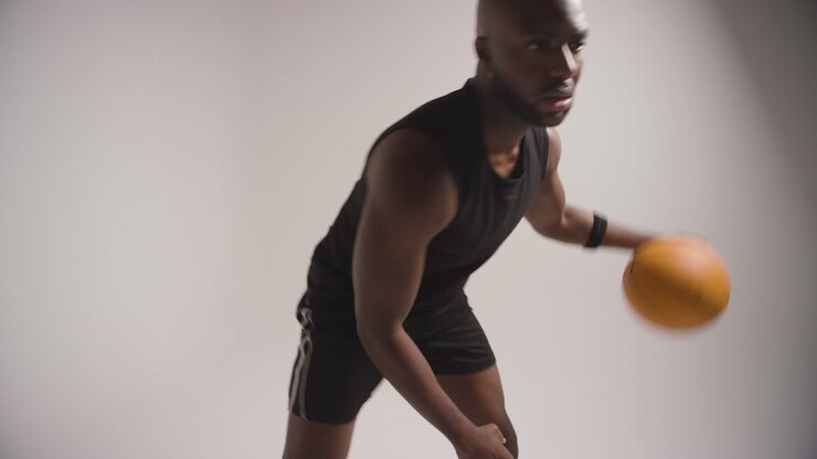 Nahaufnahme im Studio eines männlichen Basketballspielers beim Dribbeln und Prellen des Balls vor weißem Hintergrund 2