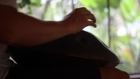 plano medio de un hombre tocando un tambor colgado o un instrumento de mano