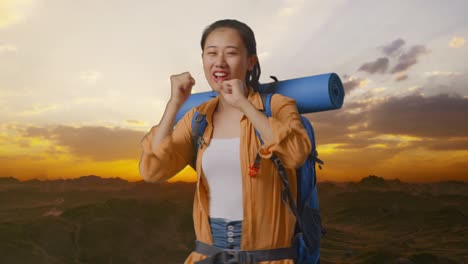 asian female hiker with mountaineering backpack enjoy dancing on the top of mountain during sunset time