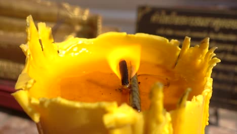 yellow burning candle with golden lying buddha on background in a temple