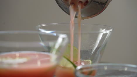verter cóctel en un vaso haciendo un cóctel de granada usando jugo de granada fresco y semillas de ron jarabe de lima y ingredientes frescos
